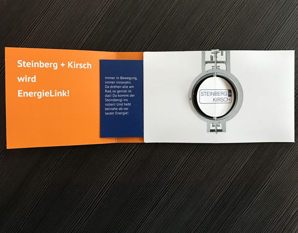 Individuelle Klappkarte. Beim Öffnen dreht sich automatisch eine ausgestanzte Papierscheibe wie ein Probeller.