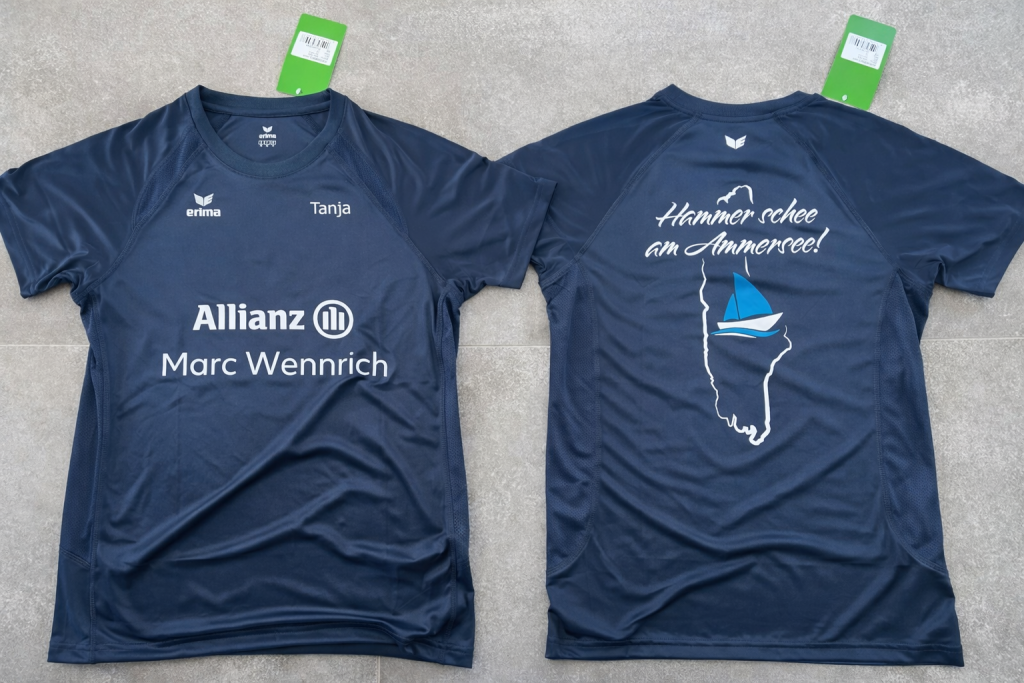 Bedrucktes Laufshirt in der Vorder- und Rückenansicht. Vorne steht der Firmenname und Name des Läufers, auf der Rückseite befindet sich der Umriss des Ammersees mit einem Segelschiff sowie der Spruch "Hammer schee am Ammersee!"